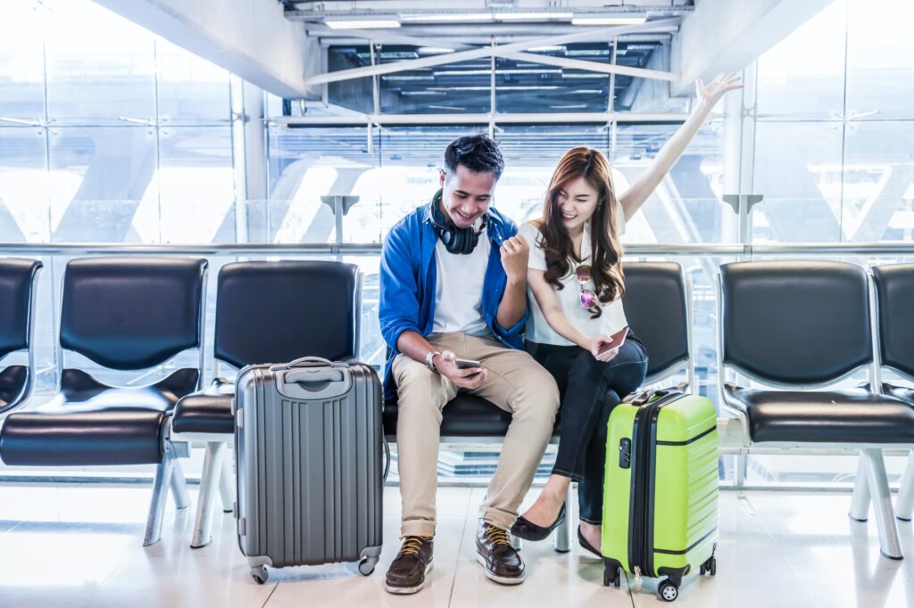 Happiness Asian couple traveler holding the passport with suitcases in modern an airport